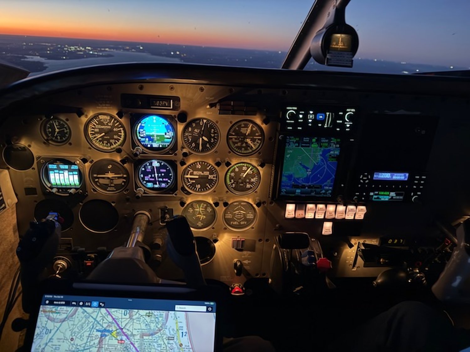 Cockpit at dusk, the panel lit up against the horizon